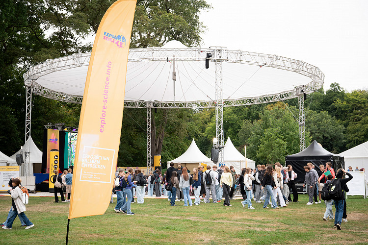 Bühne von Explore Science im Bremer Bürgerpark mit zahlreichen Besucherinnen und Besuchern vor dem Veranstaltungszelten.